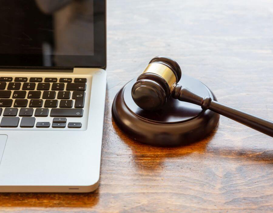 Gavel sitting next to laptop computer on a wooden desk